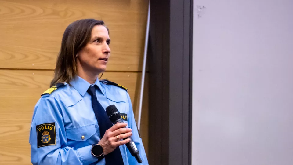 Polis Anna-Karin Boije i en aula med en mikrofon i handen.