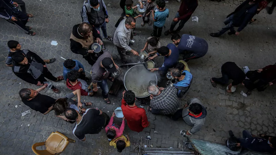 People gather to get soup from a street kitchen