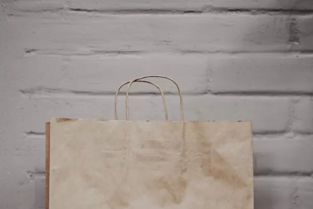 Brown paper bag in front of white brick wall