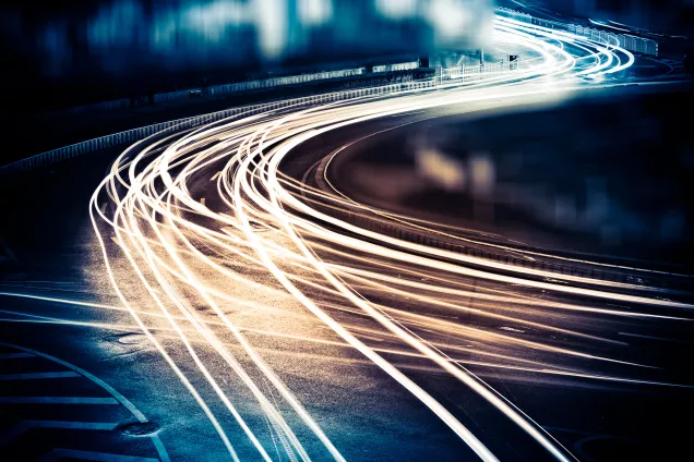 Long exposure of light from several vehicles moving over a road. Photo.