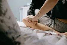 A couple sit on a bed holding hands.