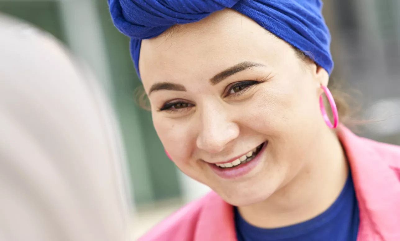 Young woman in bright pink shirt and bright blue head wrap. Photo.