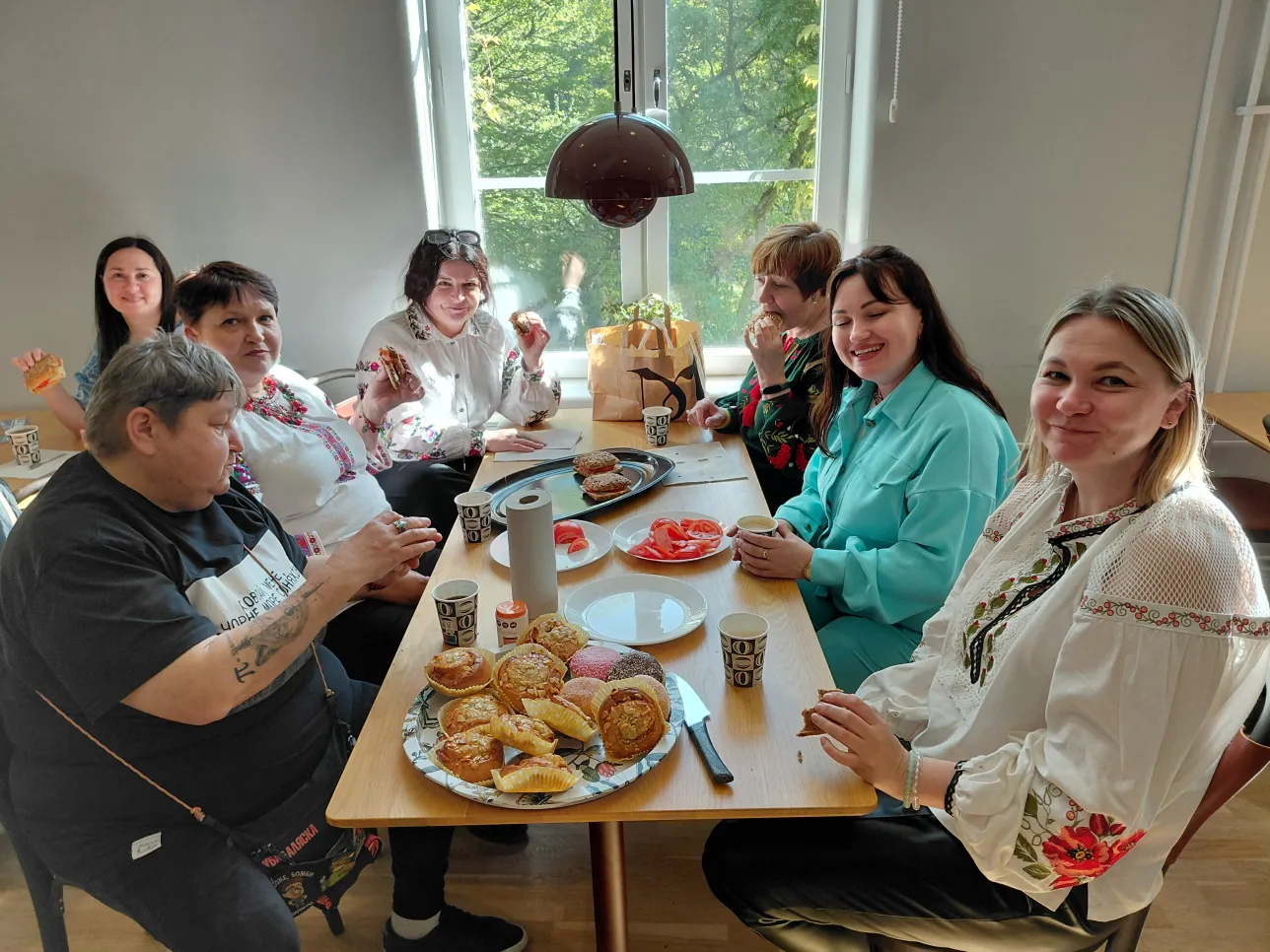 The Ukrainian women round the table with bread, tomatos and Swedish sweet buns.