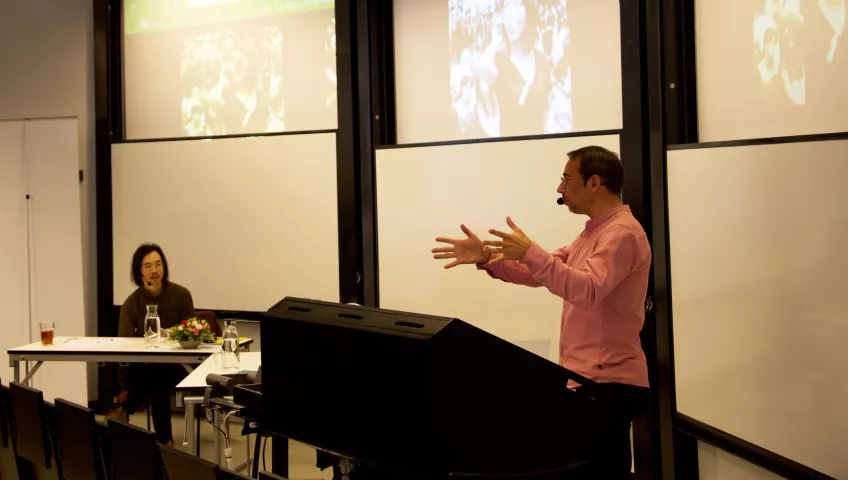 Elton Chan listens to Professor Miguel A. Martínez  - background faces blurred. Photo: Emma Lord.
