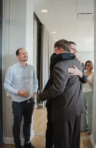 Alexander getting a hug from one of his supervisors while the other stands in line.
