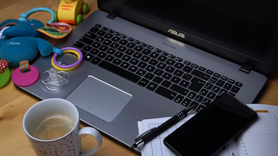 Dator och kaffekopp med barnleksaker bredvid. Foto: Pixabay. 