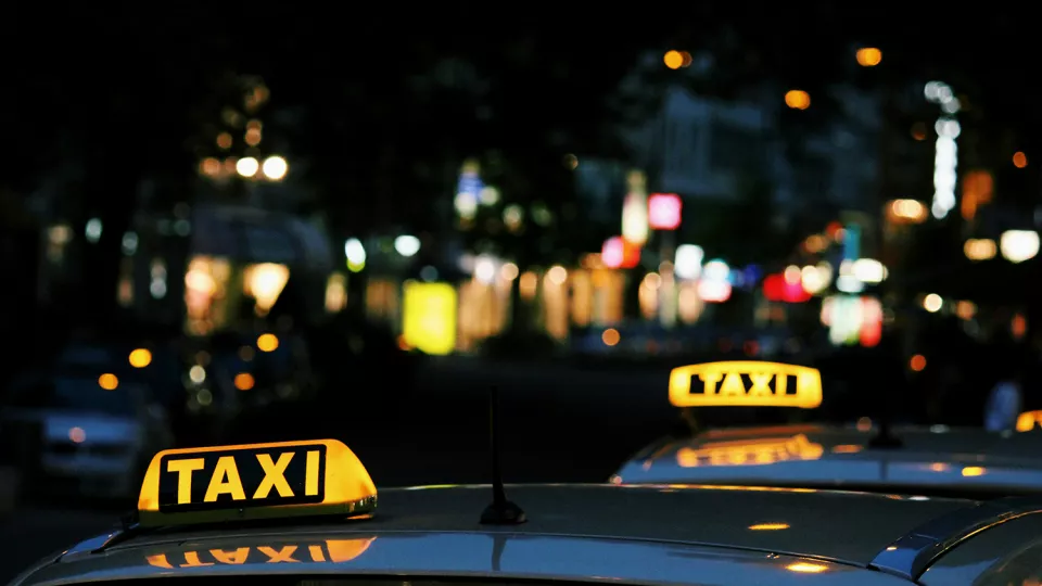 Bilar med lysande taxiskyltar i mörker.