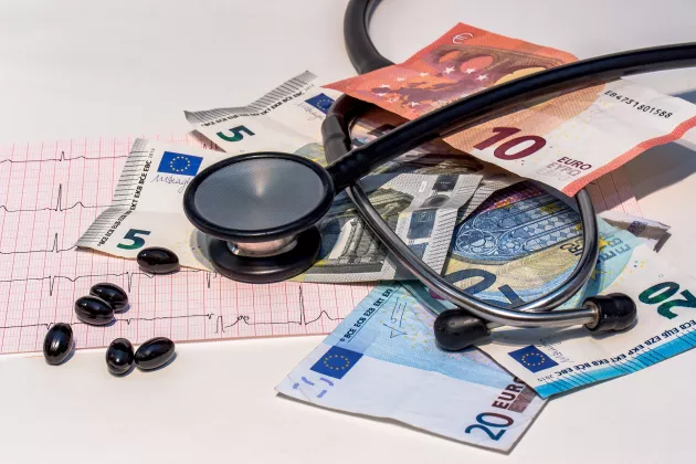 Stetoskop ligger på hög av eurosedlar och piller. Foto: Pixabay. 