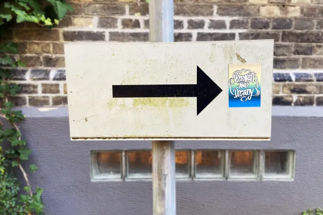 A signpost with an arrow pointing to a sticker with the text "Research and destroy". Photo: Moa Bejersten
