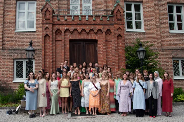 Högtidlig bild på studenter framför pampig byggnad.