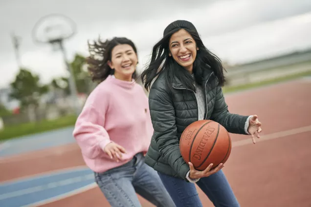 Två glada unga kvinnor spelar basket. Foto: Johan Persson.