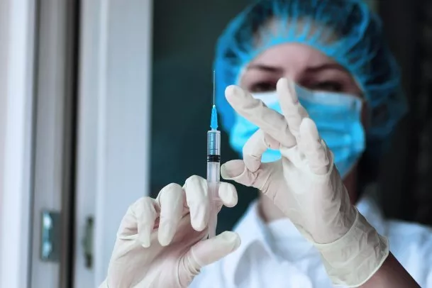 Bild på sjukvårdspersonal med spruta för att illustrera vaccin